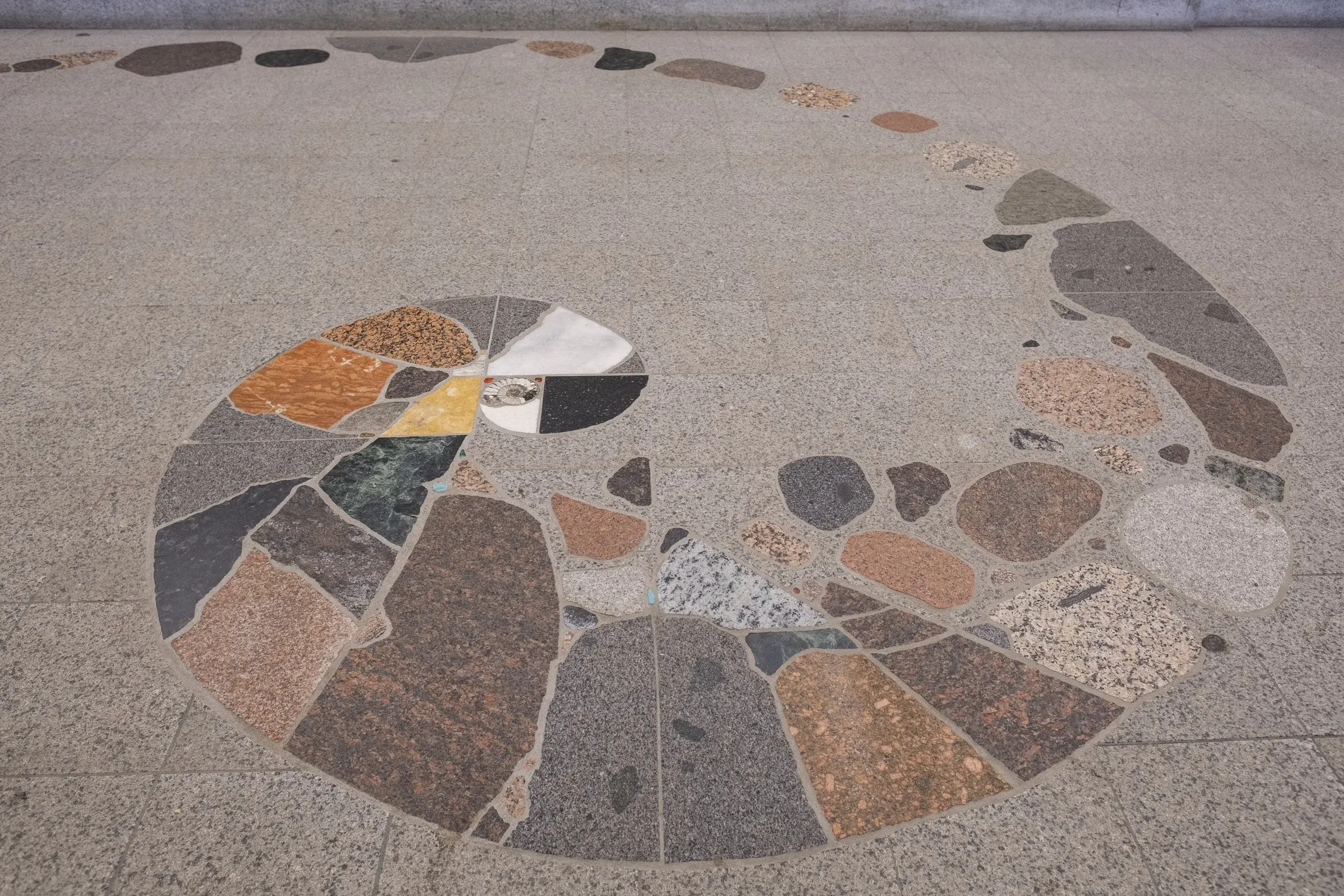 A floor design with a spiral shape made of different types and colors of rocks