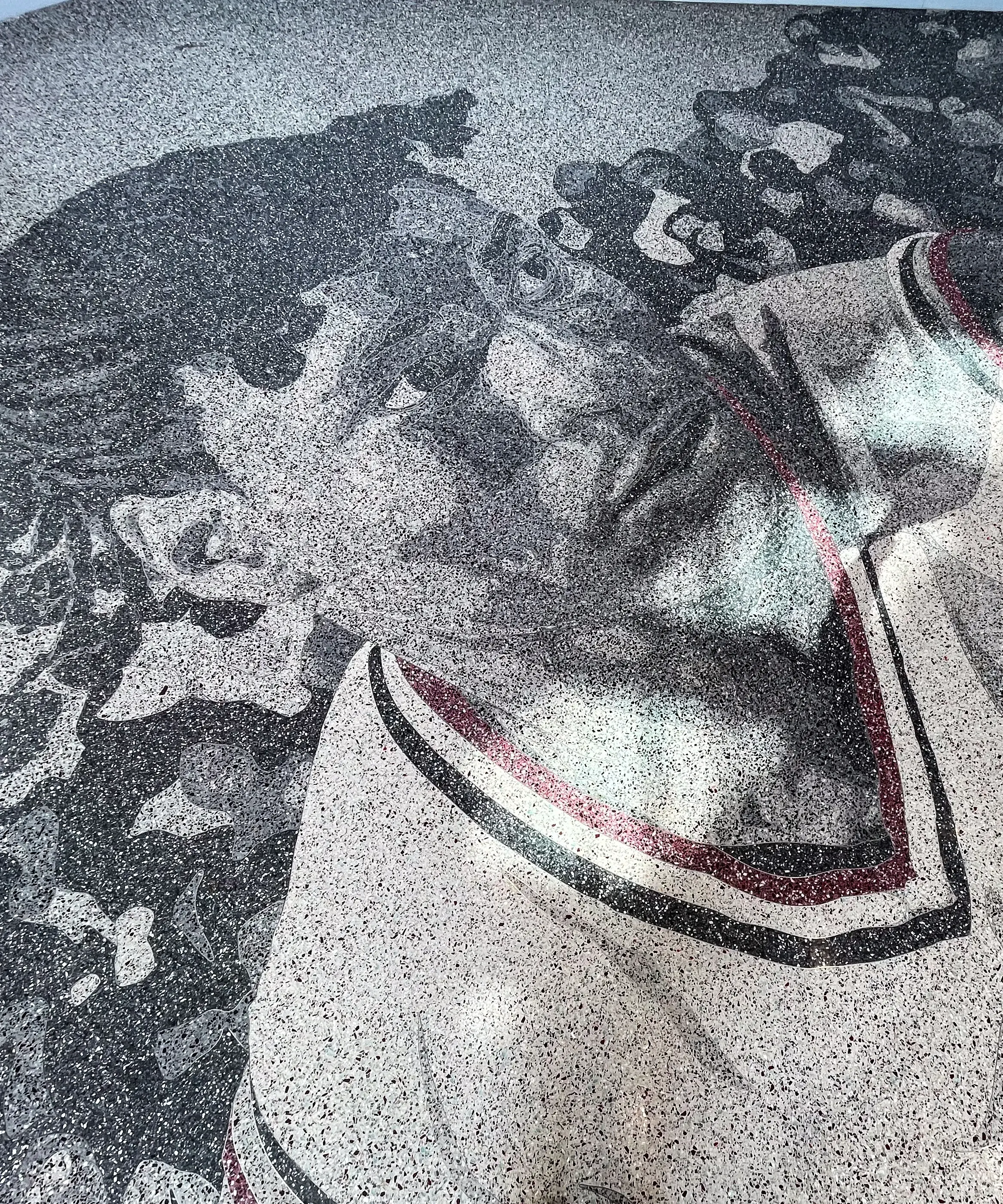 Floor design in grayscale and red shows the head and torso of a basketball player wearing a white and red Ohio State jersey in front of crowded stands.