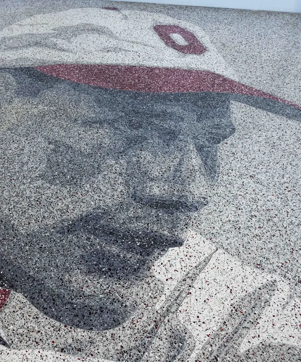 Floor design in grayscale and red of a man wearing a white and red baseball hat with an O on it