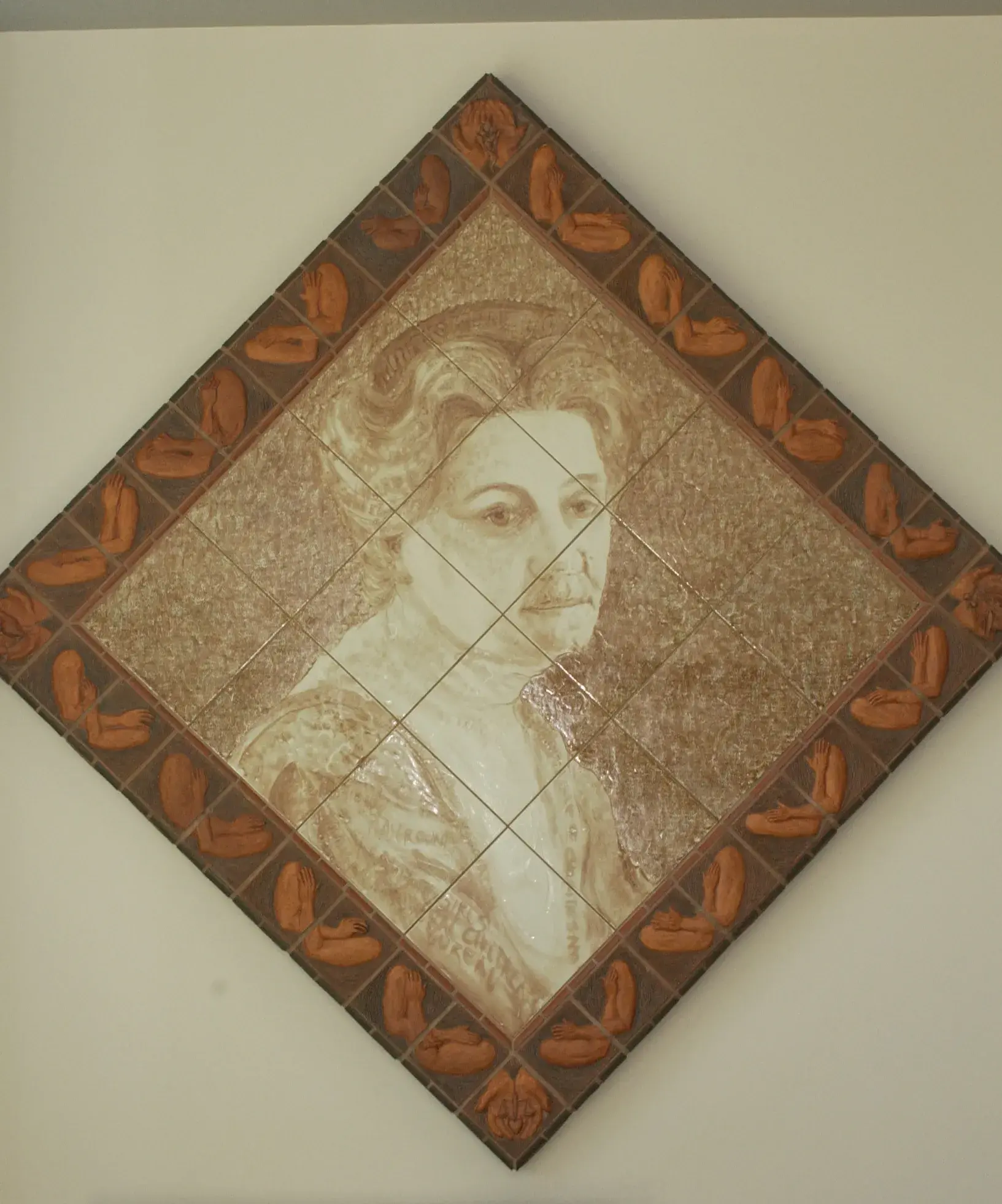 Diamond-shaped artwork made of a grid of tiles shows a historical woman's head and shoulders in sepia tones. There is a border around the artwork of a darker brown.