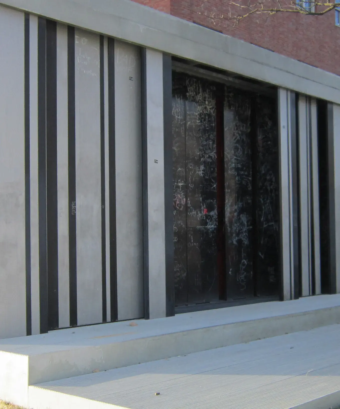 Silver metal and dark chalkboard panels are layered behind each other, with many chalk drawings and writing on the chalkboard panels