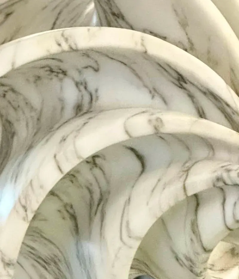 Close up of a sculpture made of swirling pieces of white and gray marble